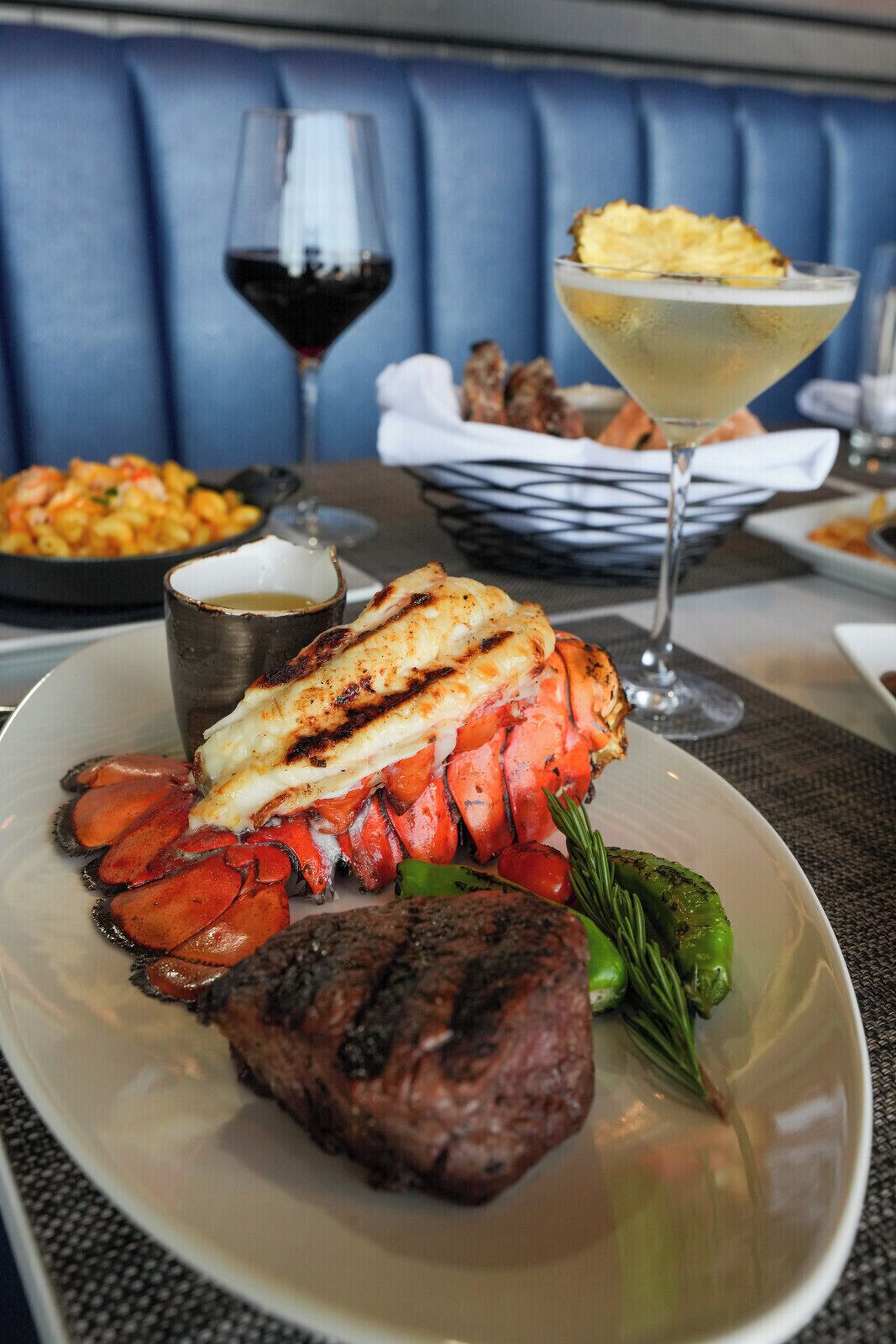 Une table à manger avec une queue de homard, un steak et des légumes.