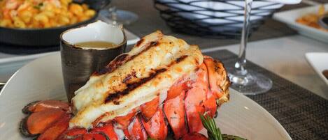 Une table à manger avec une queue de homard, un steak et des légumes.
