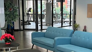A modern lobby with a blue sofa, a small round table, and a potted plant. - Grand Hotel Orlando at Universal Blvd - Shuttle to Theme Parks (Orlando)