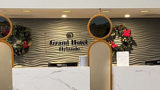 A reception desk at Grand Hotel Orlando with a marble design, two round mirrors, and festive wreaths. - Grand Hotel Orlando at Universal Blvd - Shuttle to Theme Parks (Orlando)