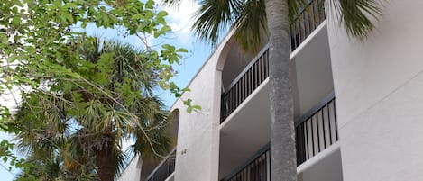 Een meerhoog gebouw met balkons en palmbomen.
