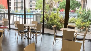 A modern indoor seating area with a view of a pool and buildings. - Grand Hotel Orlando at Universal Blvd - Shuttle to Theme Parks (Orlando)