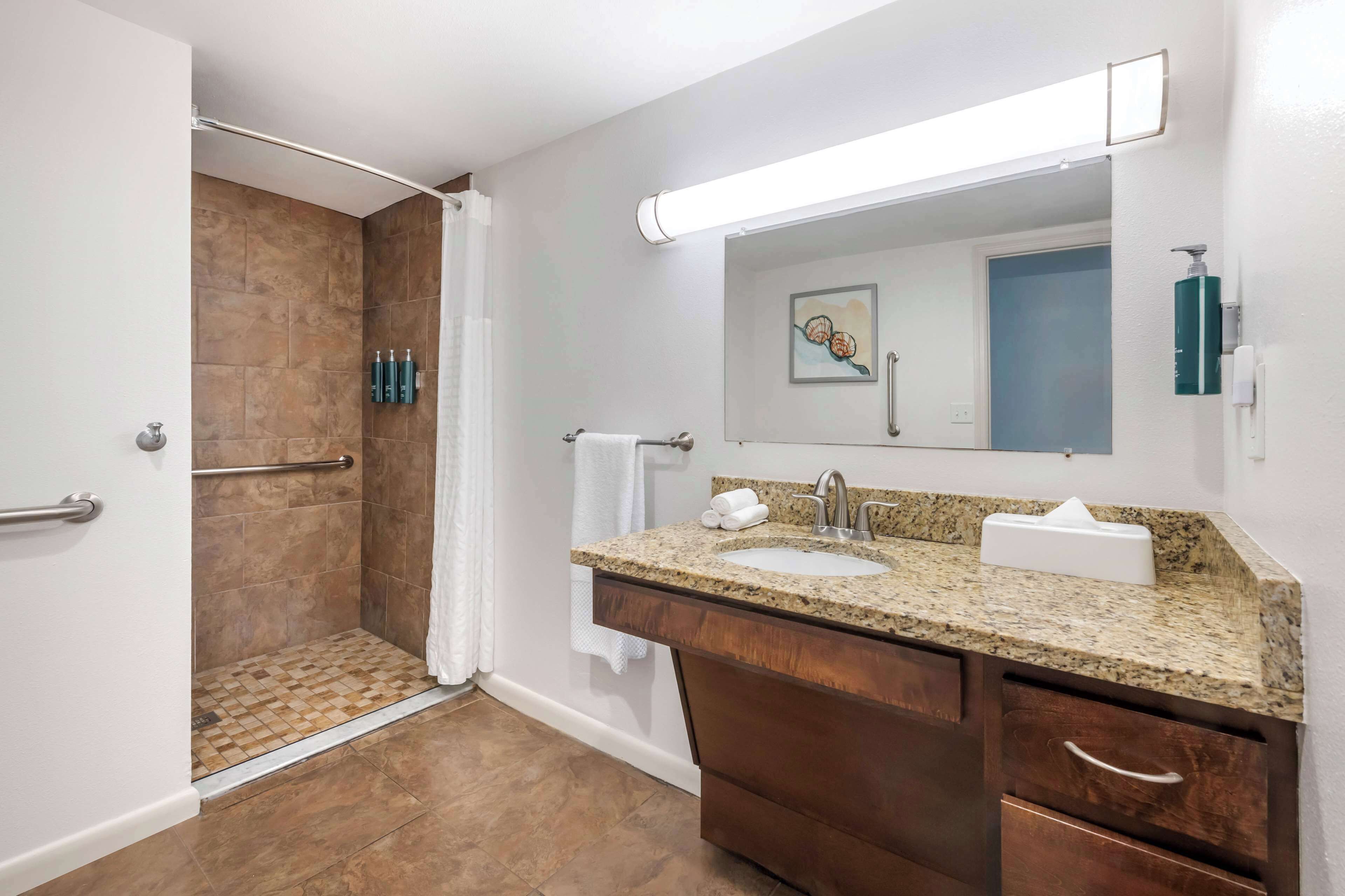 Une salle de bain moderne avec une douche, un lavabo avec un meuble-vasque et un grand miroir.