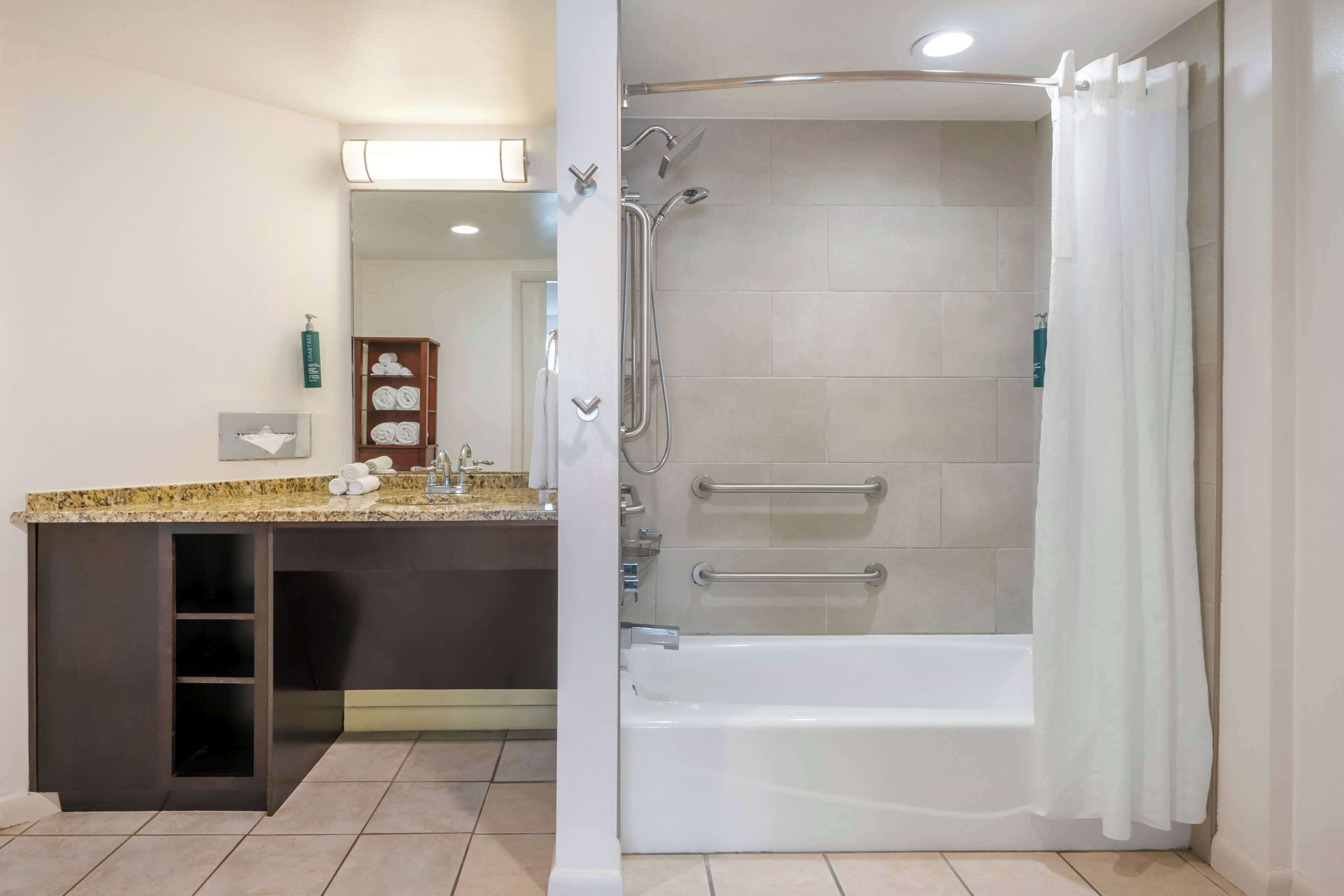 A bathroom with a shower, bathtub, and vanity with a sink.