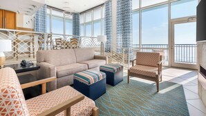Une chambre d’hôtel moderne dotée d’un grand balcon, d’un ensemble de canapés et d’un tapis à motifs.