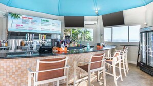 Un espace bar avec un tableau affichant le menu, des tabourets de bar et un réfrigérateur.