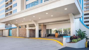 A hotel entrance with a covered walkway, a blue door, and a planter with plants.