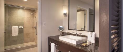 A modern bathroom with a glass-enclosed shower, a large mirror, and a vanity with a sink and towel rack.