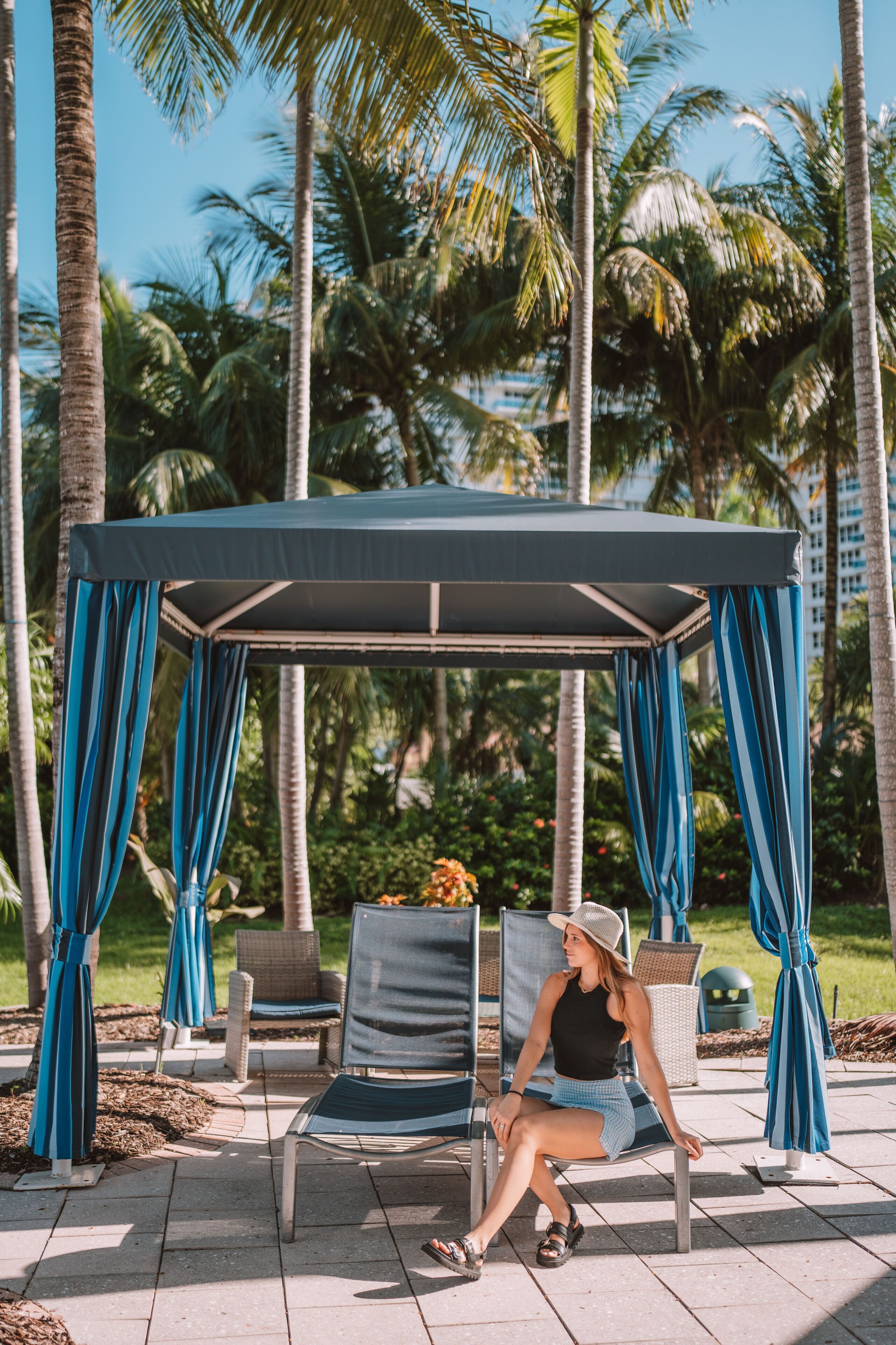 A covered outdoor seating area with a gazebo, chairs, and a person sitting.