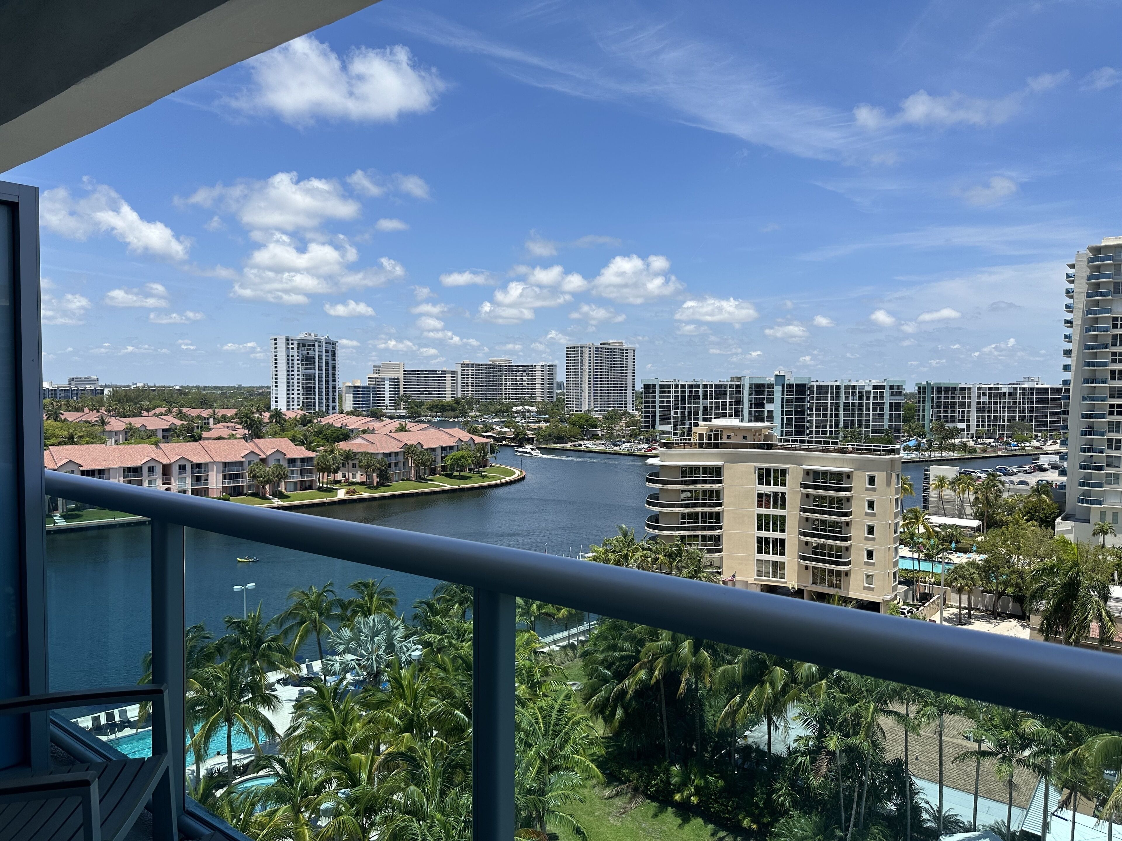 A view of a river with buildings and palm trees.