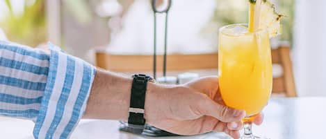 Una persona sosteniendo un vaso de jugo de naranja con una pajita, una servilleta y un plato con comida sobre una mesa.