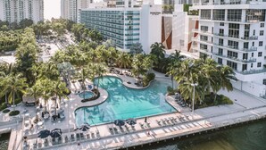 A resort with a central swimming pool surrounded by palm trees and lounge chairs. - Doubletree Resort by Hilton Hollywood Beach (Hollywood)