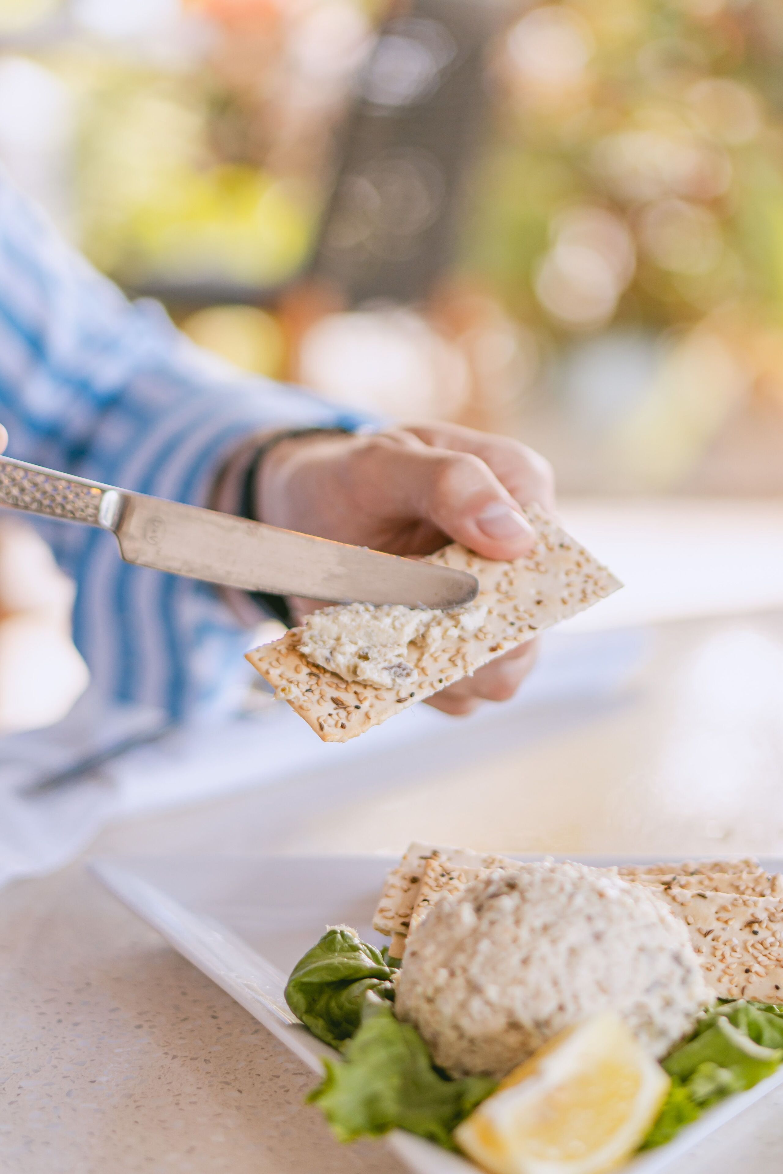 A person cutting a cracker with a knife.