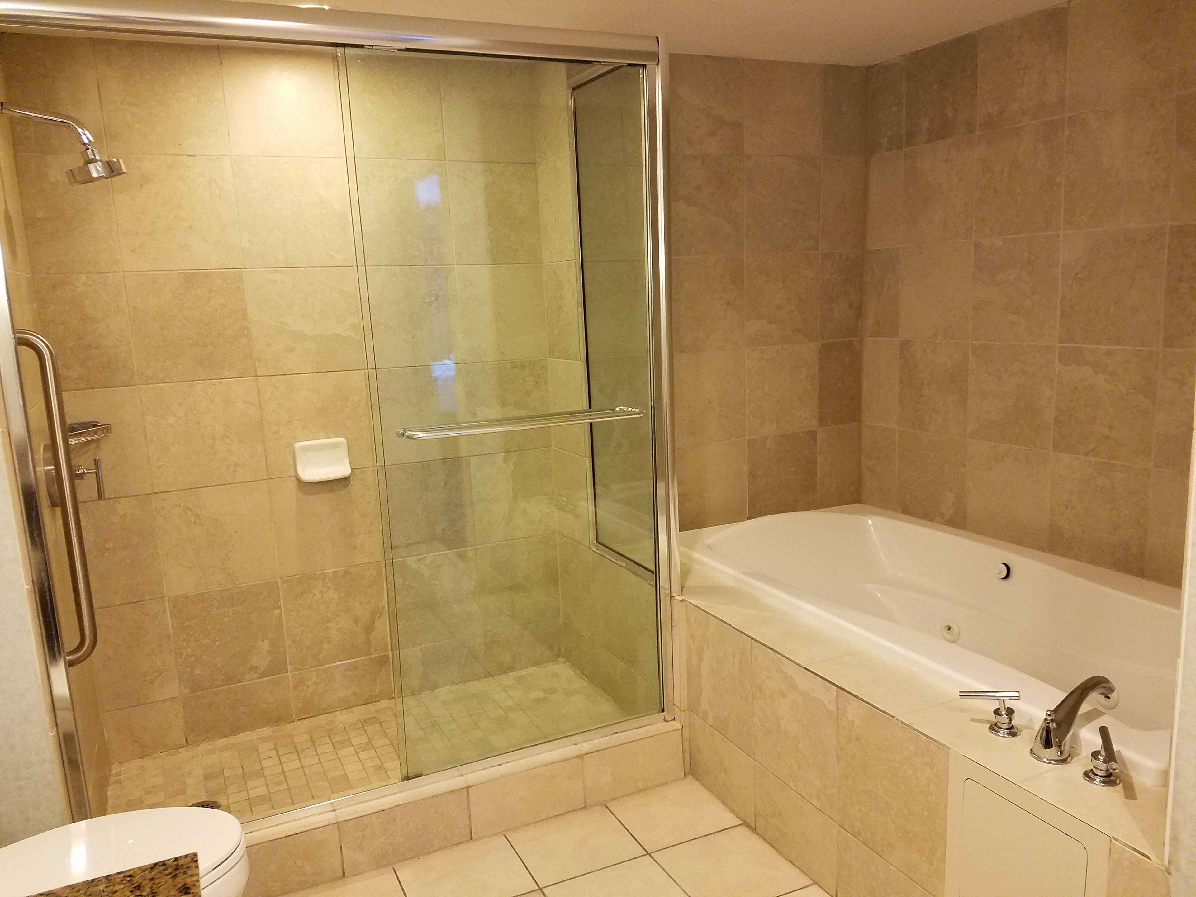Ein modernes Badezimmer mit einer gläsernen Duschkabine, einer Badewanne und einem WC.