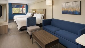 A hotel room with two beds, a blue sofa, a wooden coffee table, and a painting on the wall. - Holiday Inn Express & Suites Kendall East Miami by IHG (Miami)