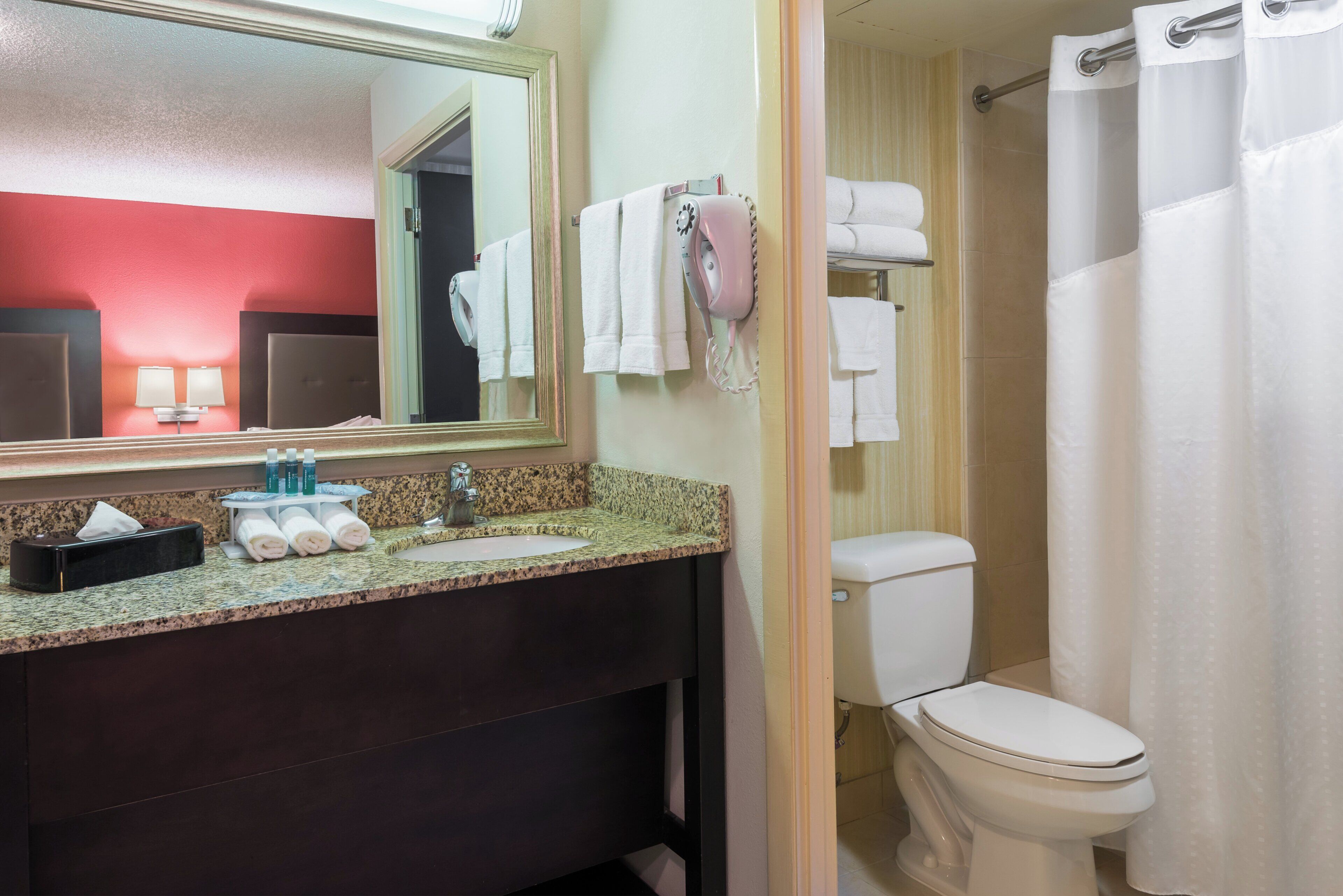 Une salle de bain équipée d’un lavabo, d’un miroir, d’un porte-serviettes et de toilettes.