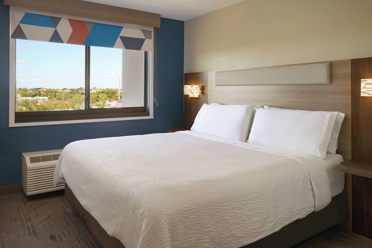Ein Hotelzimmer mit einem großen Bett, einem Fenster mit Aussicht, einer Wandleuchte und einer fest installierten Heizung.