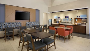 A restaurant with booths and tables, a TV mounted on the wall, and a counter with food items. - Holiday Inn Express & Suites Kendall East Miami by IHG (Miami)