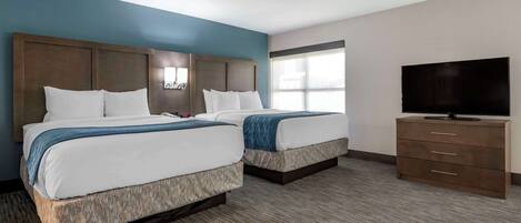 A hotel room with two beds, a TV, and a dresser.
