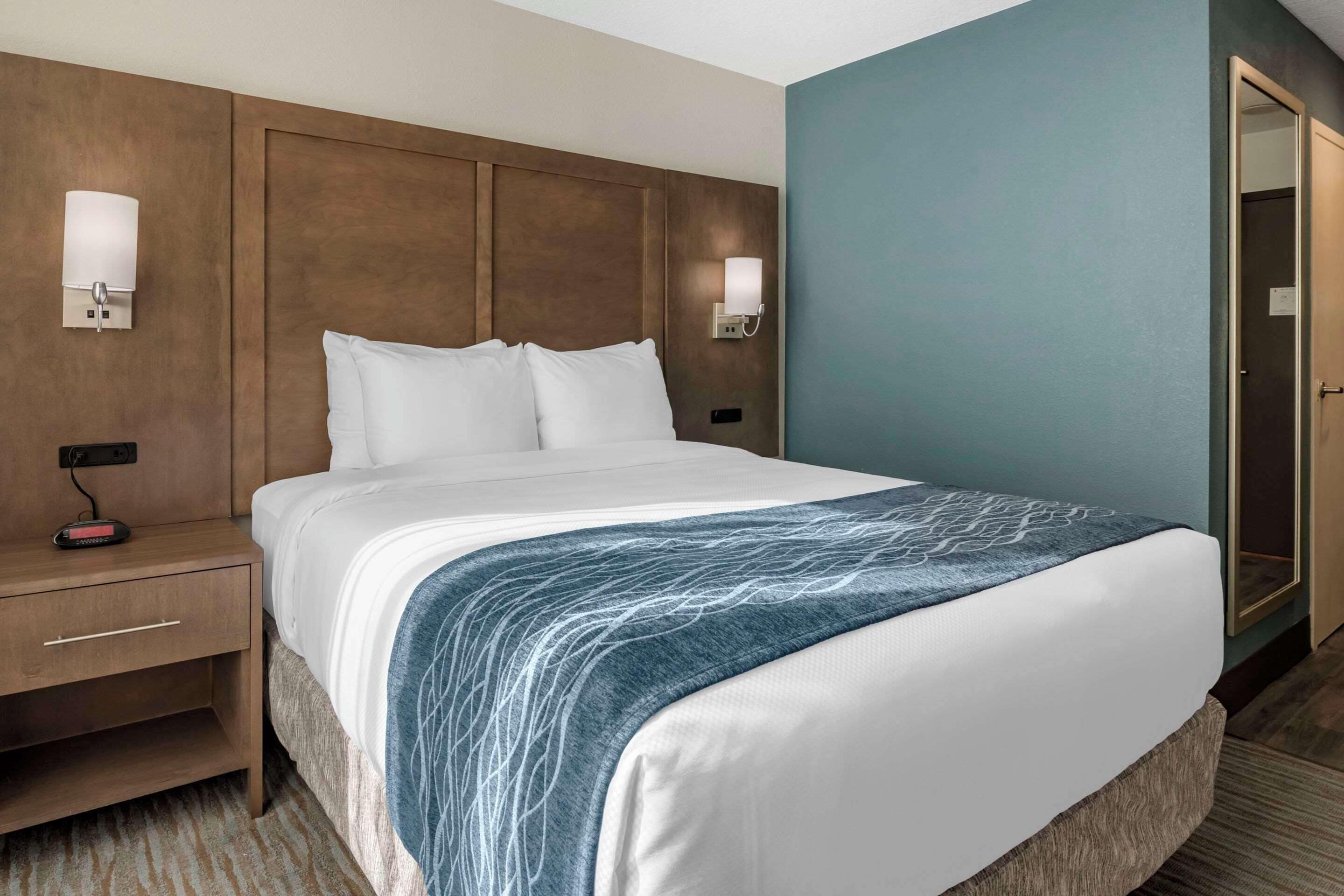A hotel room with a large bed, two bedside tables, and a nightstand.