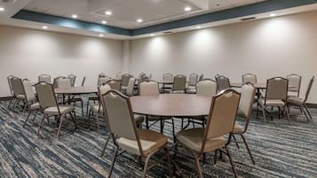 Un salón de conferencias con una gran mesa ovalada rodeada de sillas, suelo alfombrado y luces empotradas en el techo.