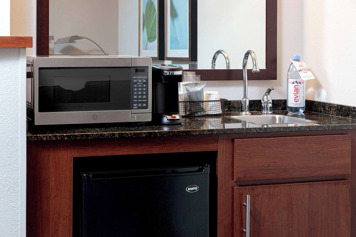 A compact kitchen with a microwave, coffee maker, and a refrigerator.