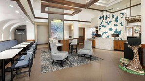 A modern hotel lobby with a reception desk, seating area, and a giraffe statue. - Hyatt Place Busch Gardens (Tampa)