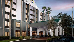 A modern hotel with a prominent entrance, large windows, and palm trees. - Hyatt Place Busch Gardens (Tampa)