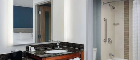 A modern bathroom with a marble sink, wooden vanity, and a separate shower area.