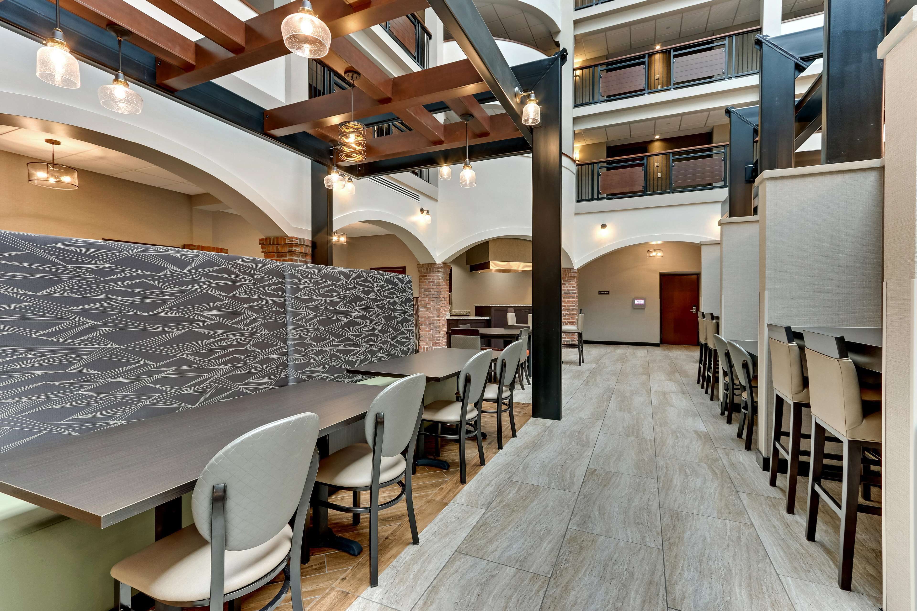 A modern restaurant with high ceilings, exposed beams, and a mix of seating options including booths and tables.