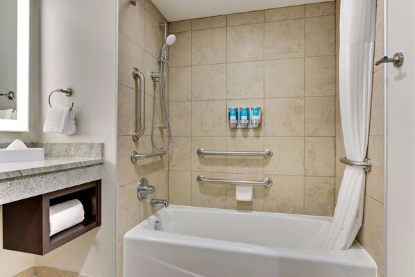 A bathroom with a bathtub, a shower, a towel rack, and a shelf with toiletries.