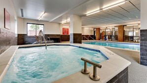 A hotel lobby with a large indoor swimming pool, a staircase, and a seating area with tables and chairs. - Drury Plaza Hotel St. Paul Downtown (St. Paul)