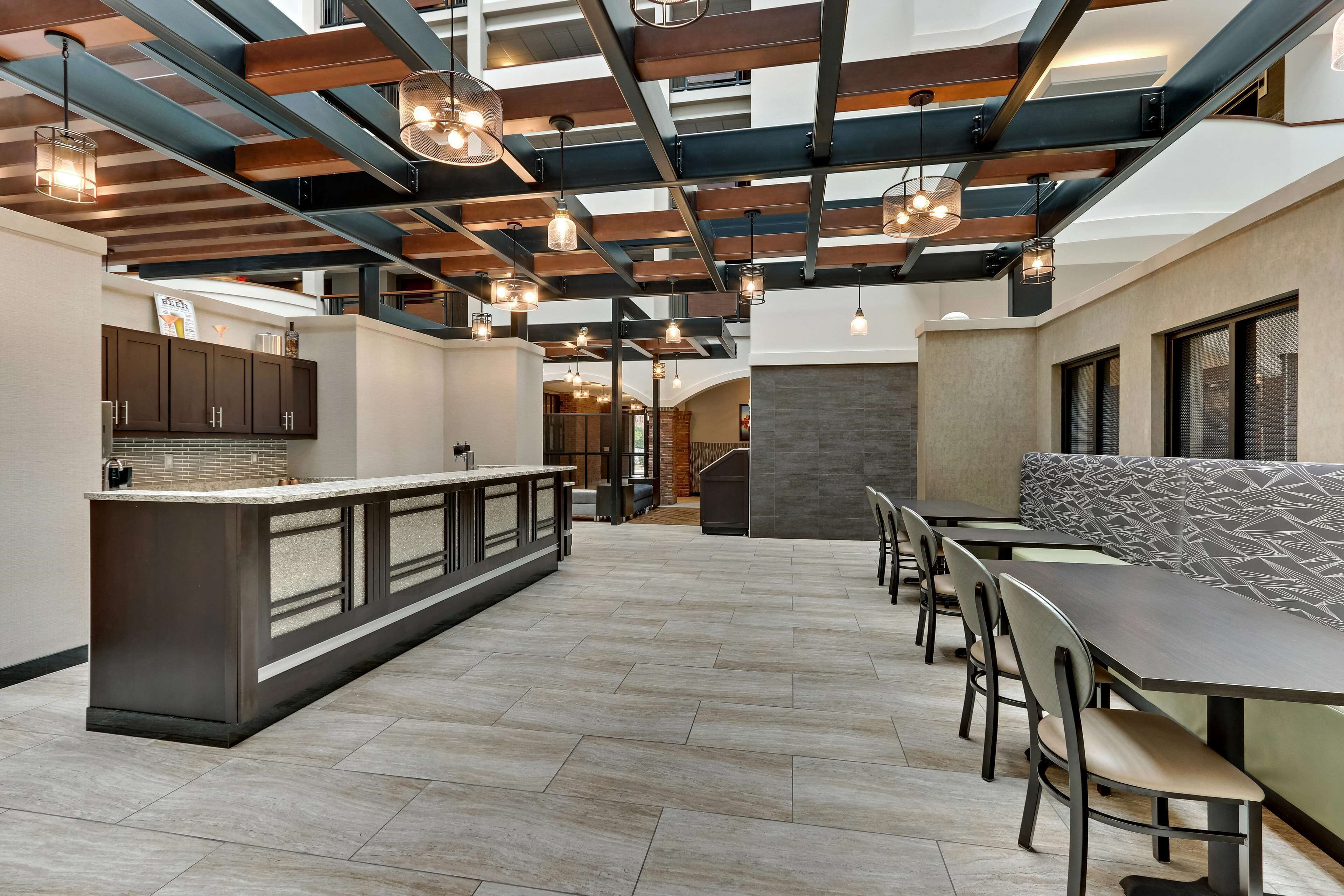 Une cuisine moderne dotée d’un îlot central, de meubles de rangement en bois foncé et de luminaires suspendus.