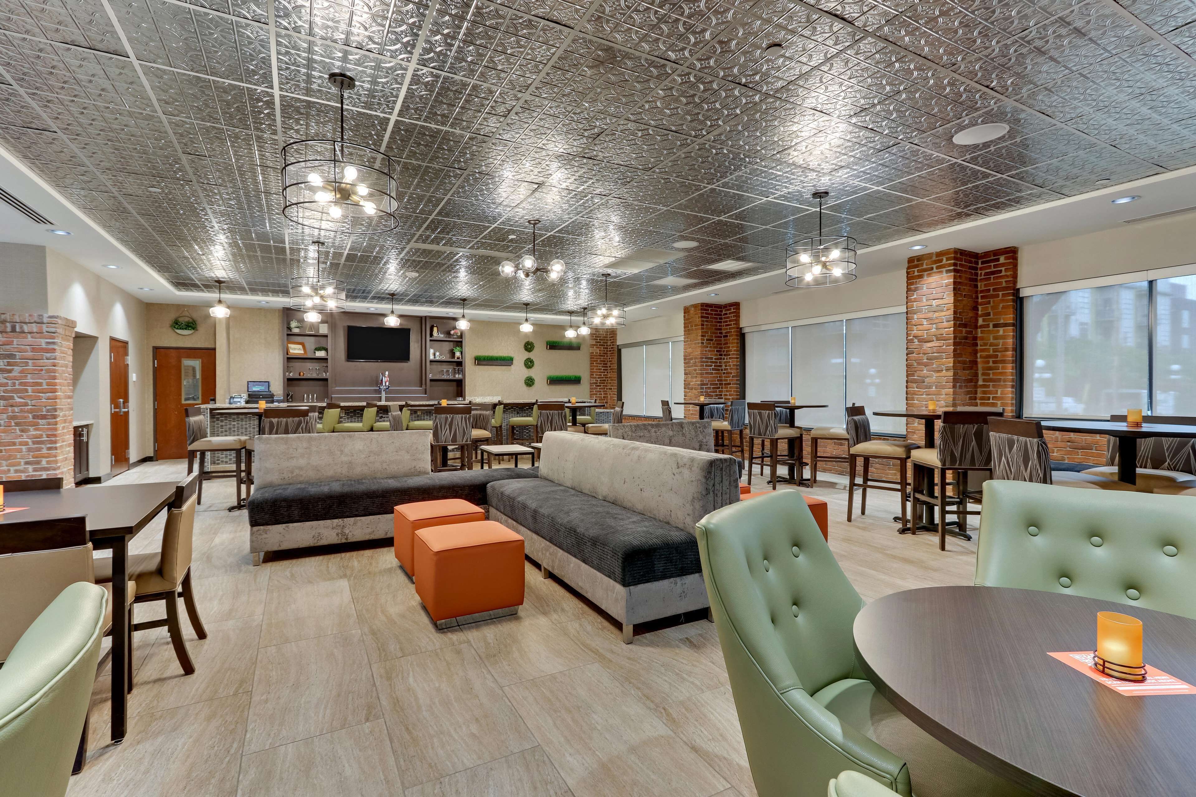 Amplia sala de estar con diseño moderno, que incluye un sofá modular grande, otomanas naranjas y diversas opciones de asiento.