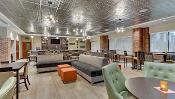 A spacious lounge area with a modern design, featuring a large sectional sofa, orange ottomans, and a variety of seating options.