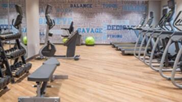 Een fitnessruimte met loopbanden, hometrainers en krachtapparaten.