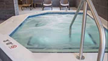 A hot tub with a metal ladder, a sign indicating a 30-minute use limit, and two chairs in the background.