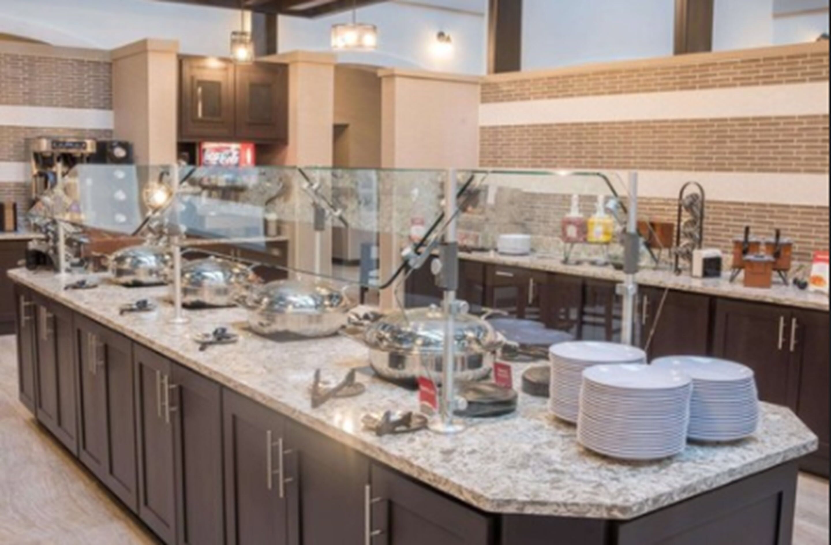 A buffet-style kitchen with a granite countertop, stainless steel appliances, and a brick accent wall.