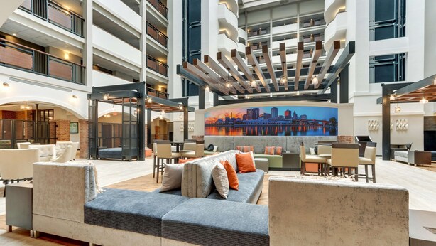 A spacious lobby with a high ceiling, a large sofa, and a cityscape mural. - Drury Plaza Hotel St. Paul Downtown (St. Paul)