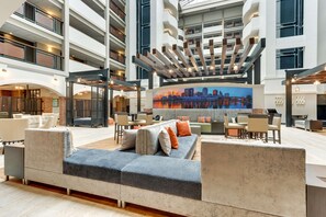 A spacious lobby with a high ceiling, a large sofa, and a cityscape mural. - Drury Plaza Hotel St. Paul Downtown (St. Paul)