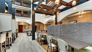 A modern hotel lobby with a high ceiling, exposed beams, and a central seating area with tables and chairs. - Drury Plaza Hotel St. Paul Downtown (St. Paul)