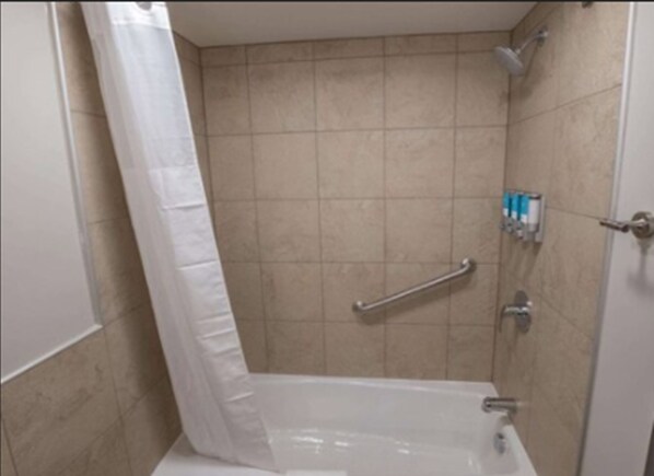 A bathroom with a shower, a grab bar, and a toilet.