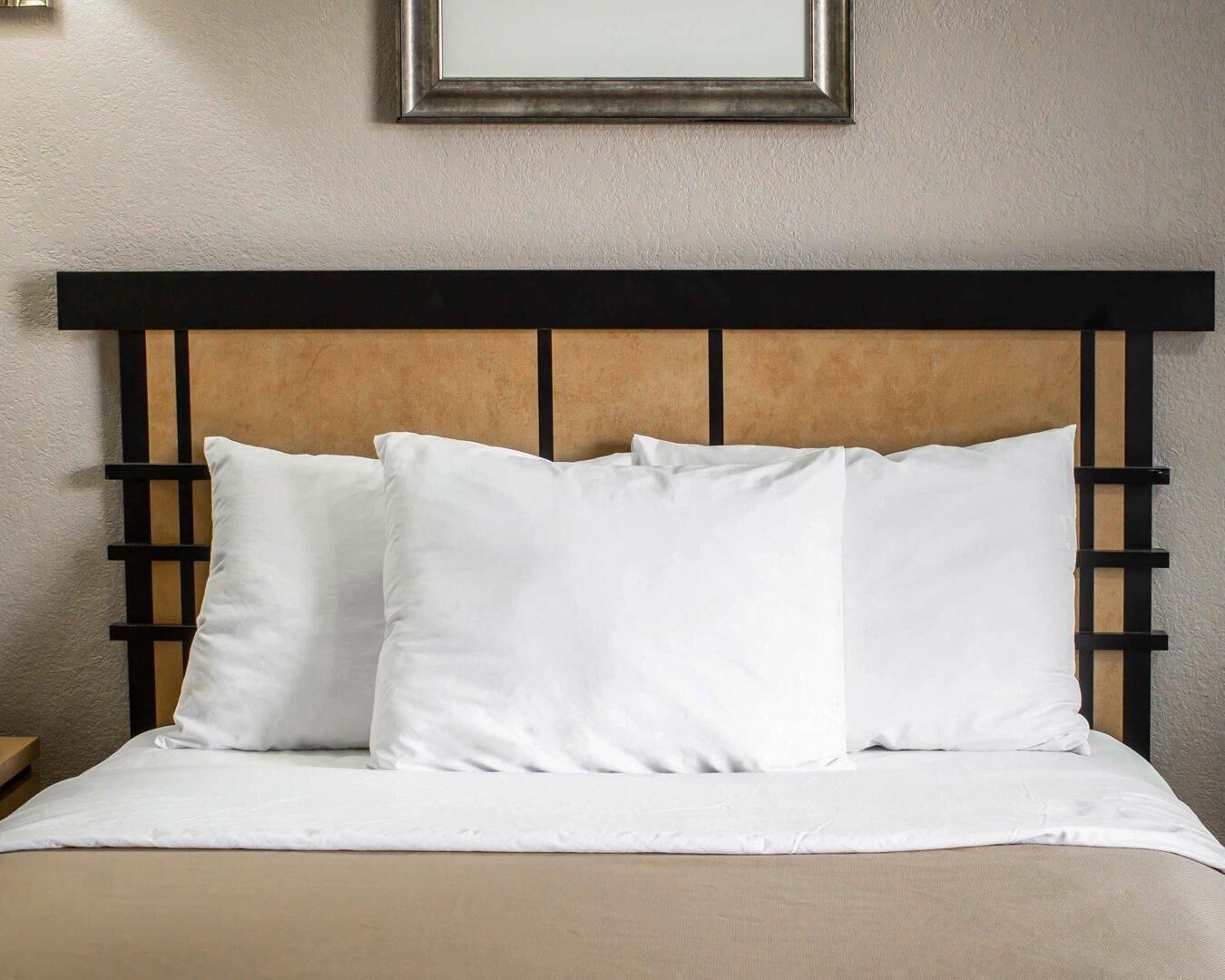 A bed with a wooden headboard and white bedding.