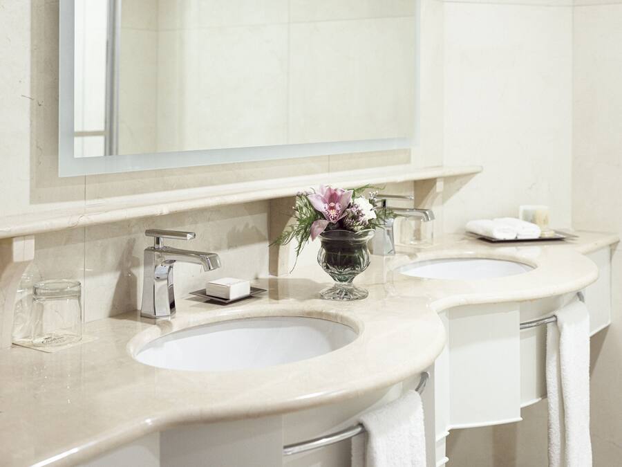 A bathroom with two sinks, a large mirror, and a vase with flowers.