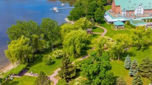 Vue aérienne d’un hôtel comprenant un grand bâtiment, un lac et un jardin bien entretenu avec des allées.