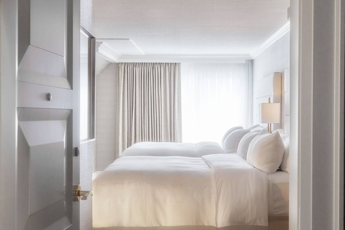 Une chambre d’hôtel avec un grand lit, une fenêtre avec des rideaux et un sol recouvert de moquette.