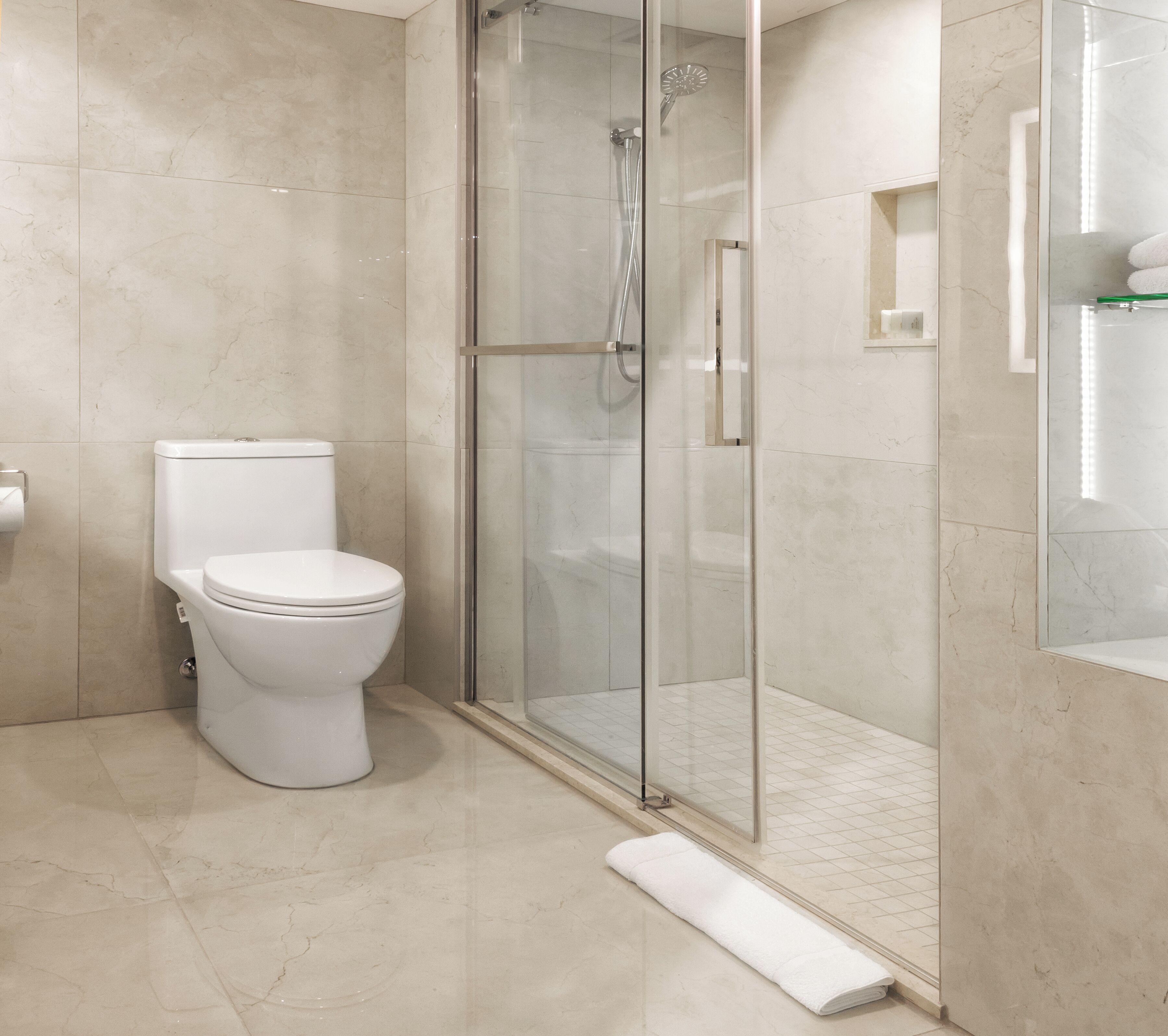 A modern bathroom with a toilet, a glass-enclosed shower, and a tiled floor.