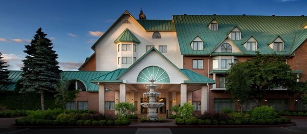 Un gran hotel de varios pisos con una entrada destacada que incluye una fuente.