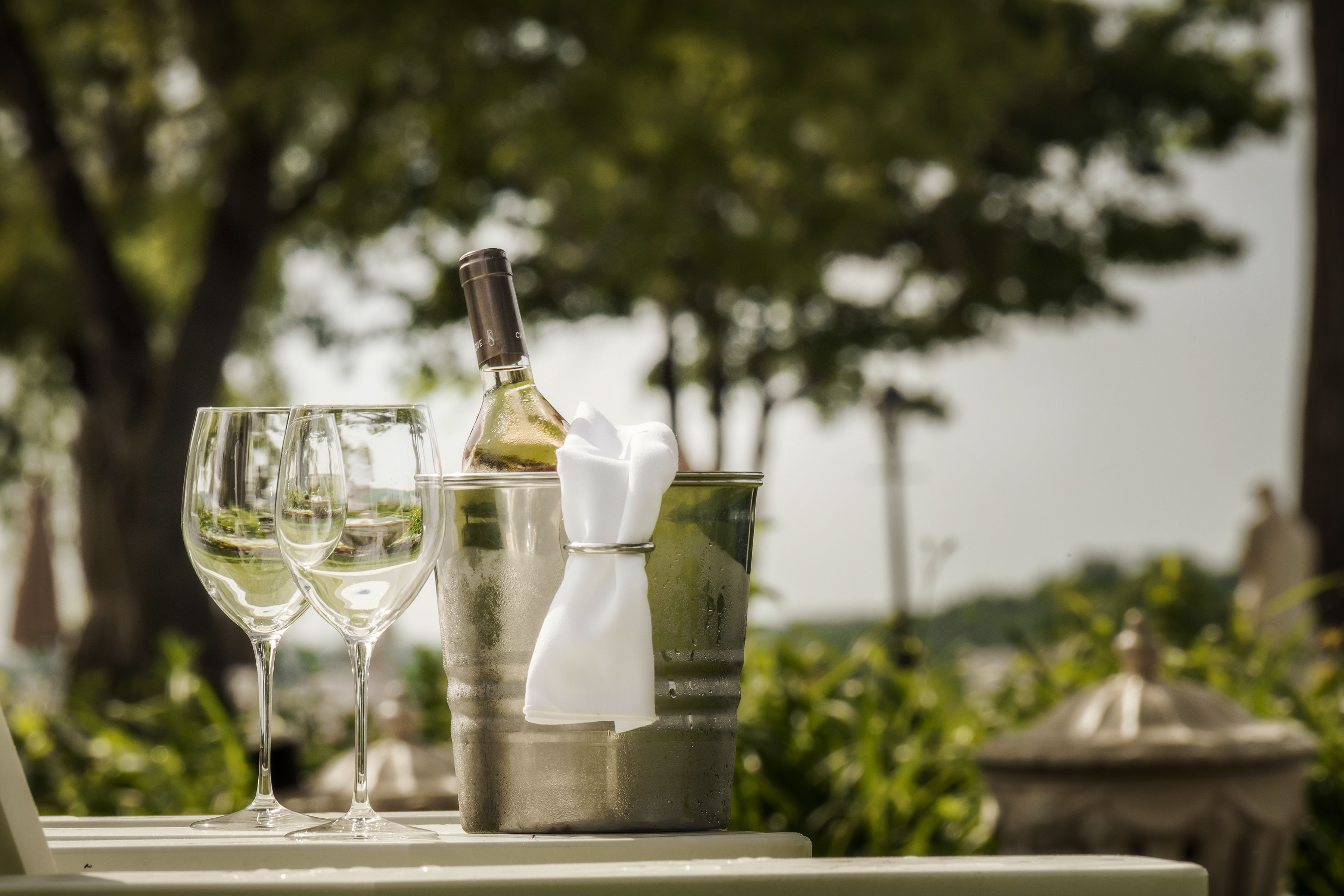 A table with two wine glasses and a bottle of wine in a metal container.