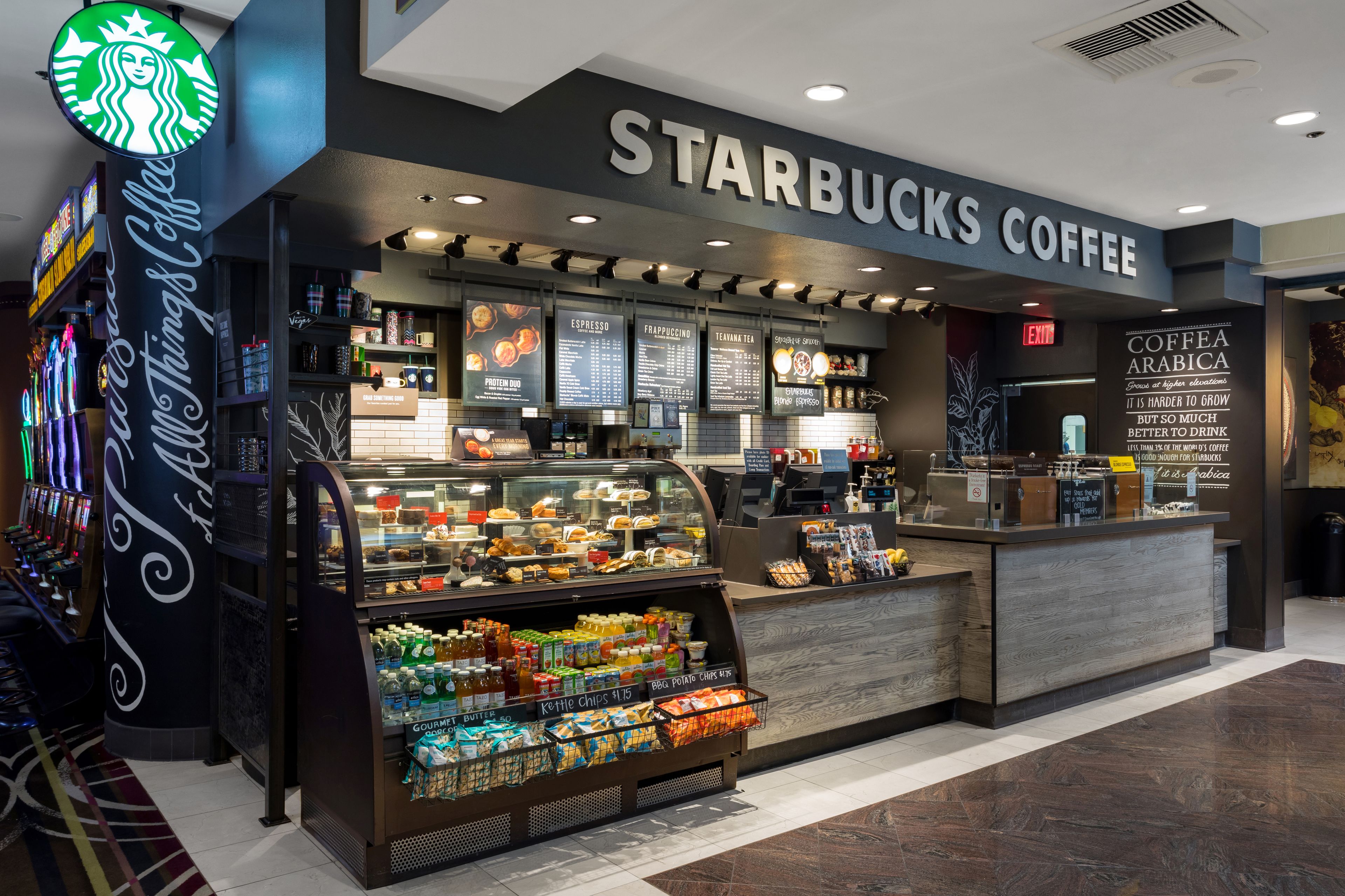 Ένα κατάστημα Starbucks με ποικιλία ροφημάτων και σνακ, έναν πίνακα με το μενού και μια πινακίδα που υποδεικνύει την έξοδο.